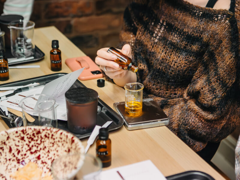 Woman adding drops of essential oil to a beaker to make perfume